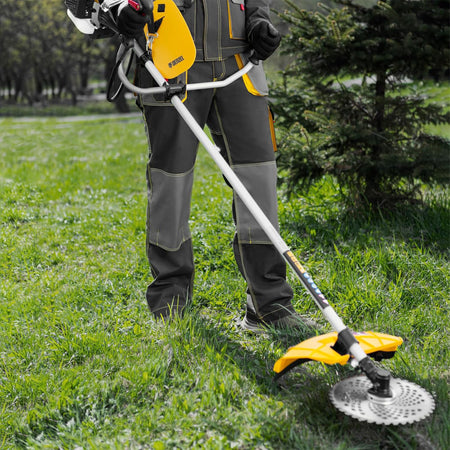 Person using a yellow and black grass trimmer in a grassy area