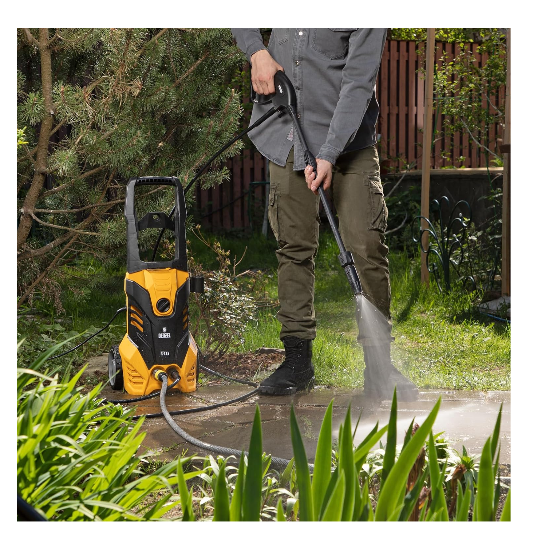 Person using a yellow and black pressure washer in a garden setting