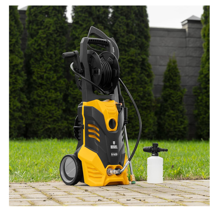 Yellow and black pressure washer on a wooden deck with grass and trees in the background