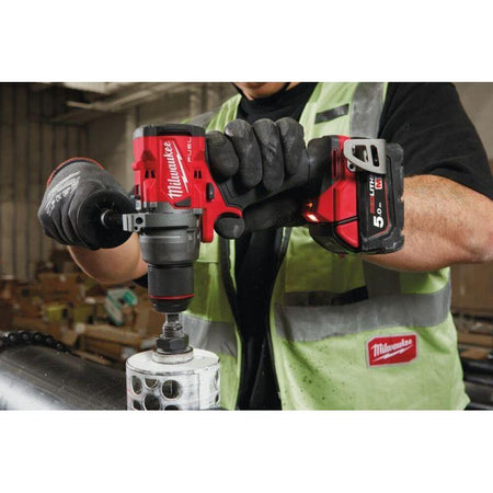 Person using a Milwaukee power drill in a workshop setting