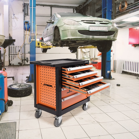 Orange tool cart with open drawers in a garage setting with a car on a lift.