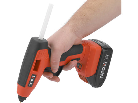 Hand holding a red and black Yato cordless drill on a white background
