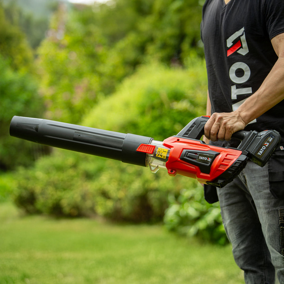 Person holding a red and black leaf blower in a garden setting
