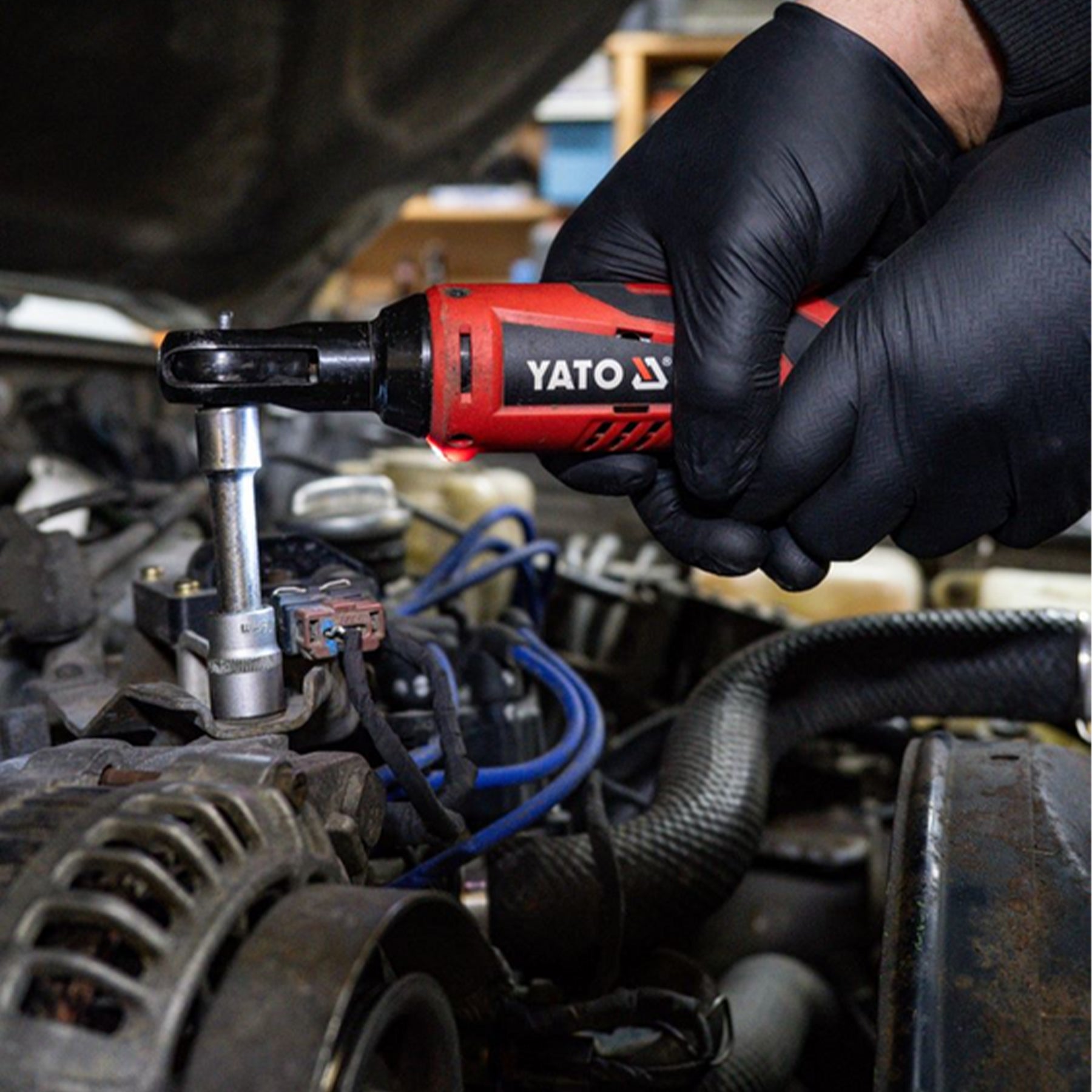 Person using a YATO impact wrench on a car engine