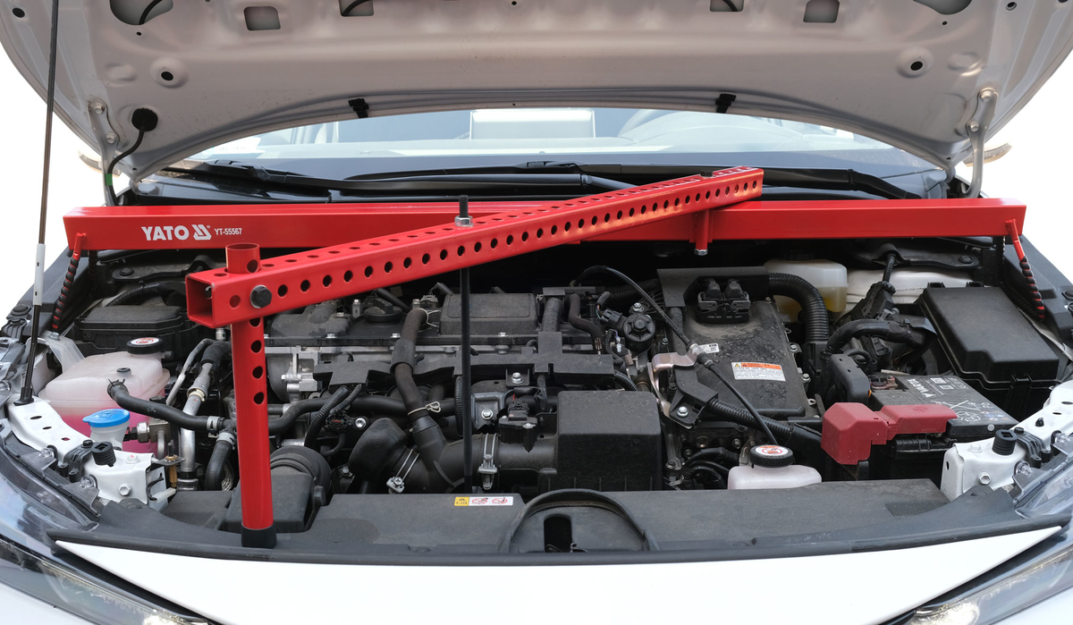 Red YATO car lift inside an open car hood